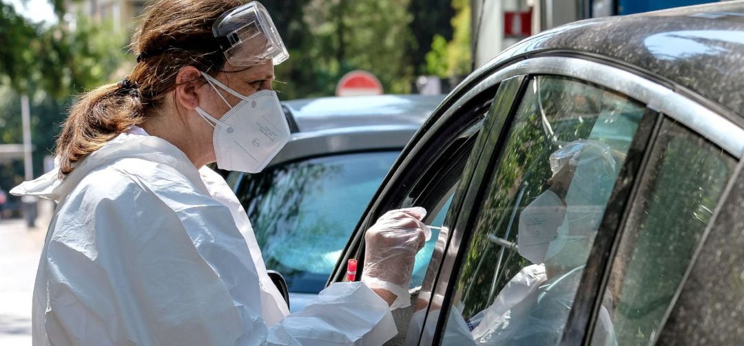 Una enfermera realiza un test de coronavirus a un paciente en el interior de un vehículo.