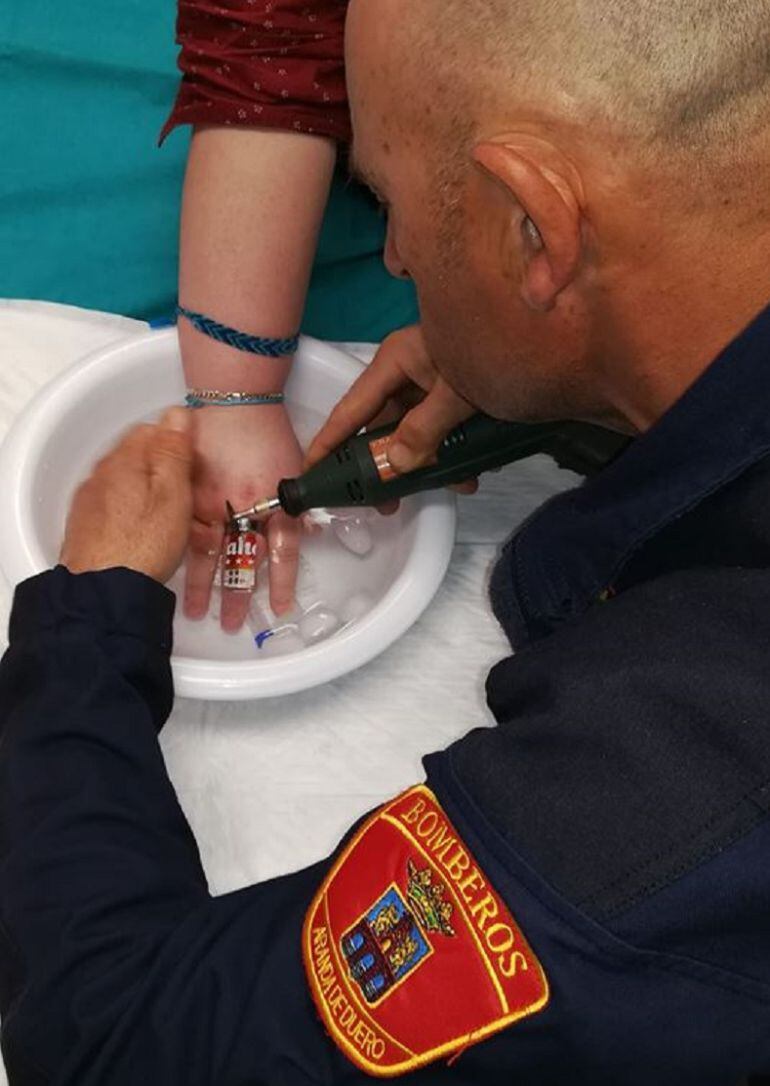 Un miembro del cuerpo de Bomberos de Aranda utiliza una pequeña sierra de precisión para retirar un anillo encajado en el dedo de una paciente