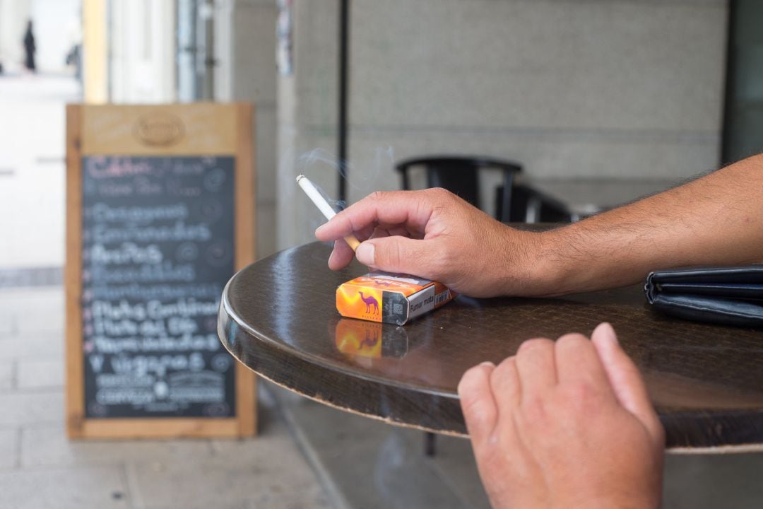 Una persona fuma en una terraza durante el primer día de la prohibición de realizarlo en la vía pública