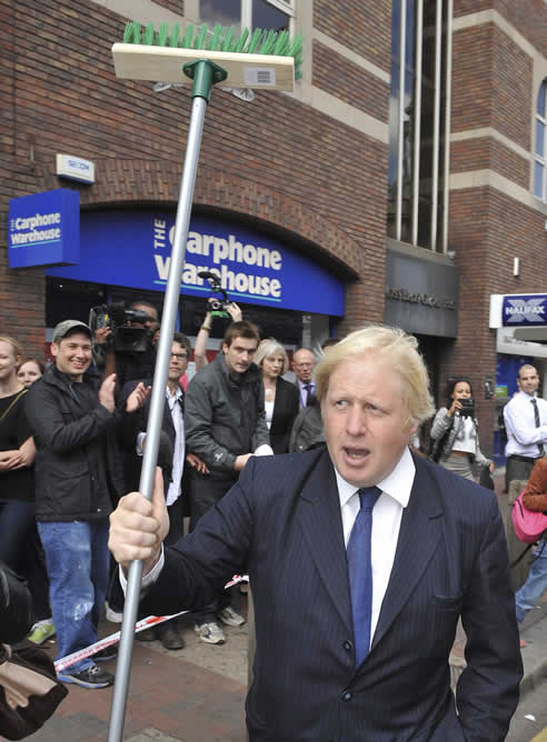 El alcalde de Londres, Boris Johnson, sostiene una escoba y dice un discurso a miembros de la comunidad en las afueras de la estación de tren de Clapham Juntion, después de los disturbios en Londres y otros sitios de Reino Unido