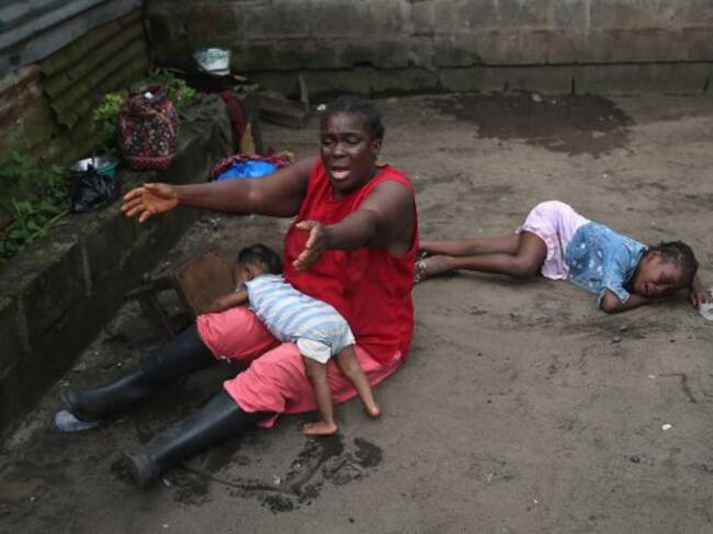 MONROVIA, LIBERIA - OCTOBER 10: Sophia Doe sits with her grandchildren Beauty Mandi, 9 months (L) and Arthuneh Qunoh, 9, (R), while watching the arrival an Ebola burial team to take away the body of her daughter Mekie Nagbe, 28, for cremation on October 1
