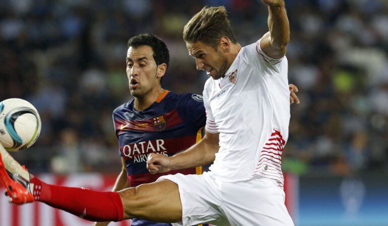 GRA216. TIFLIS (GEORGIA), 11/08/2015.- El defensa polaco del Sevilla, Grzegorz Krychowiak (d), despeja la pelota ante el centrocampista del FC Barcelona Sergio Busquets (i), durante el partido de la Supercopa de Europa que se juega hoy en el estadio Boris Paichadze Dinamo Arena, en Tiflis (Georgia). EFE/Kiko Huesca