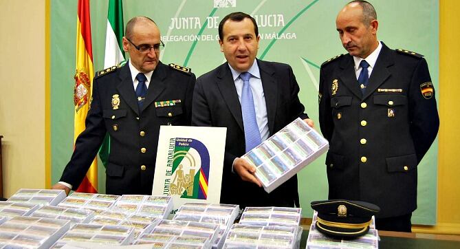 El delegado del Gobierno Andaluz, José Luis Ruiz Espejo, flanqueado por responsables policiales, muestra los boletos de lotería ilegales intervenidos