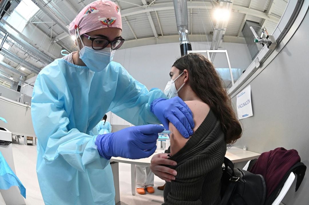 Una sanitaria pone la vacuna contra la covid-19 a una mujer durante el inicio del proceso de vacunación puesto en marcha en el pabellón 3 del hospital Enfermera Isabel Zendal, este martes en Madrid.