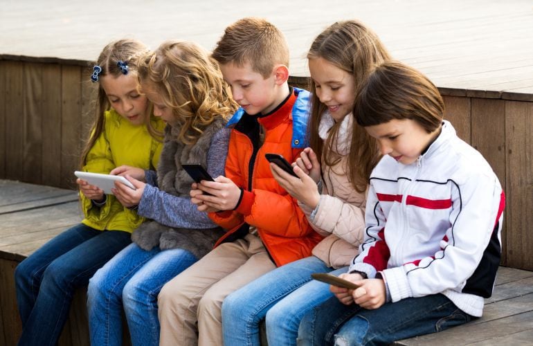 Un grupo de chicos utiliza tabletas y teléfonos móviles.