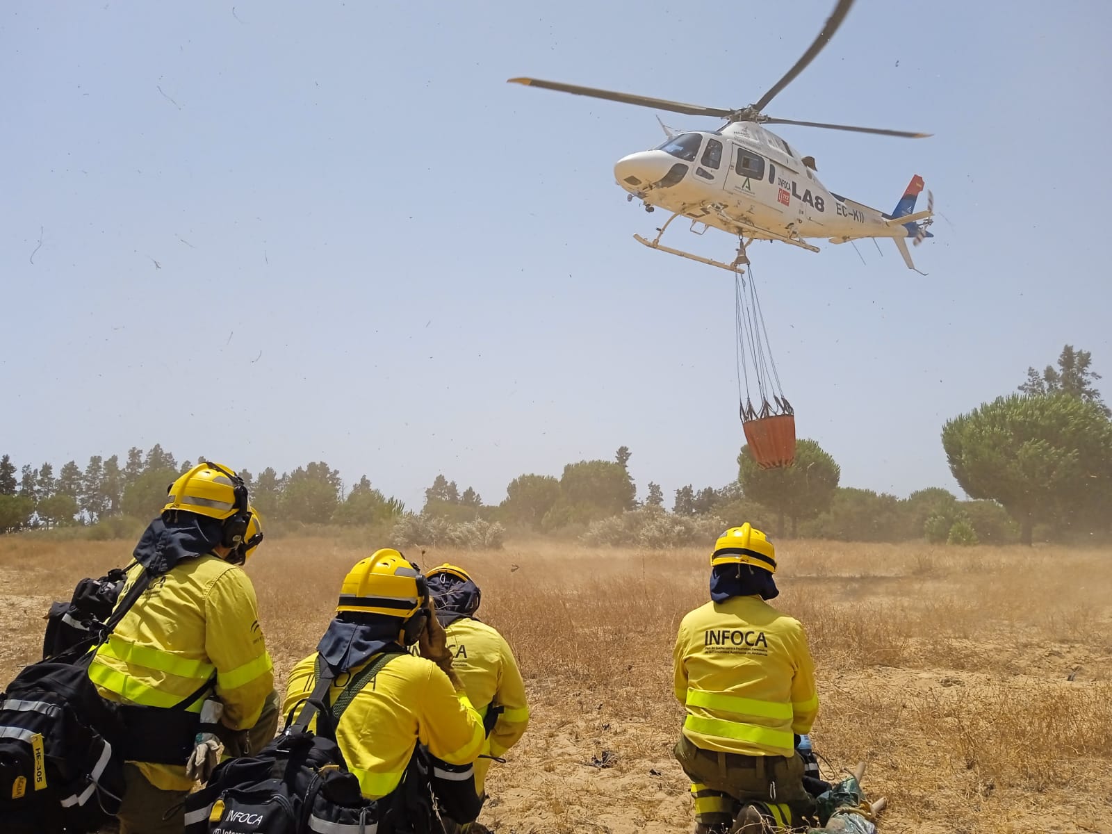 Bomberos del Plan Infoca esperan, en tierra, la llegada de un helicóptero