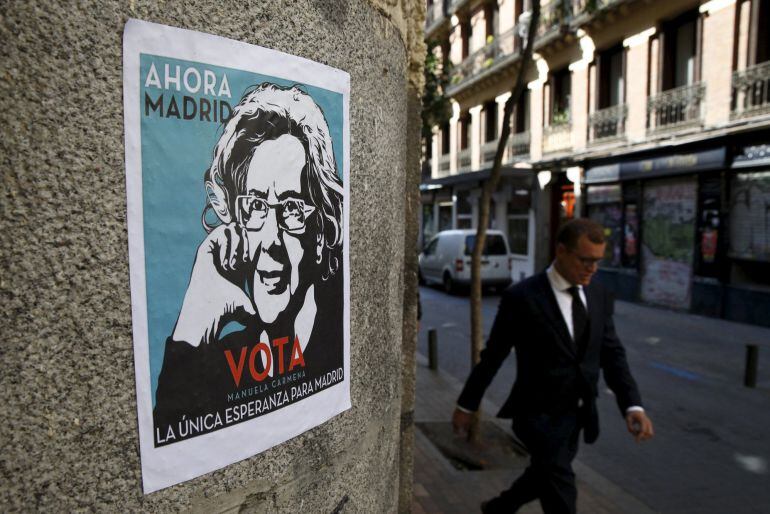 A man walks past an electoral poster of Ahora Madrid (Madrid Now) local candidate Manuela Carmena in Madrid, Spain, May 20, 2015. Spaniards are expected to sweep aside 40 years of predictable politics when they vote in regional elections on Sunday and ush