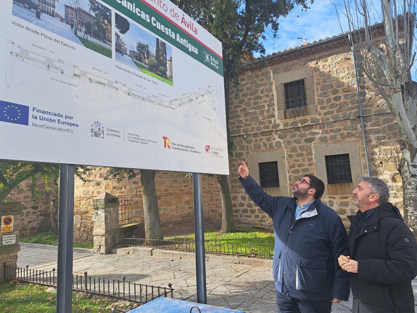 El alcalde y el concejal de obras observan el cartel donde se informa del proyecto de las escaleras