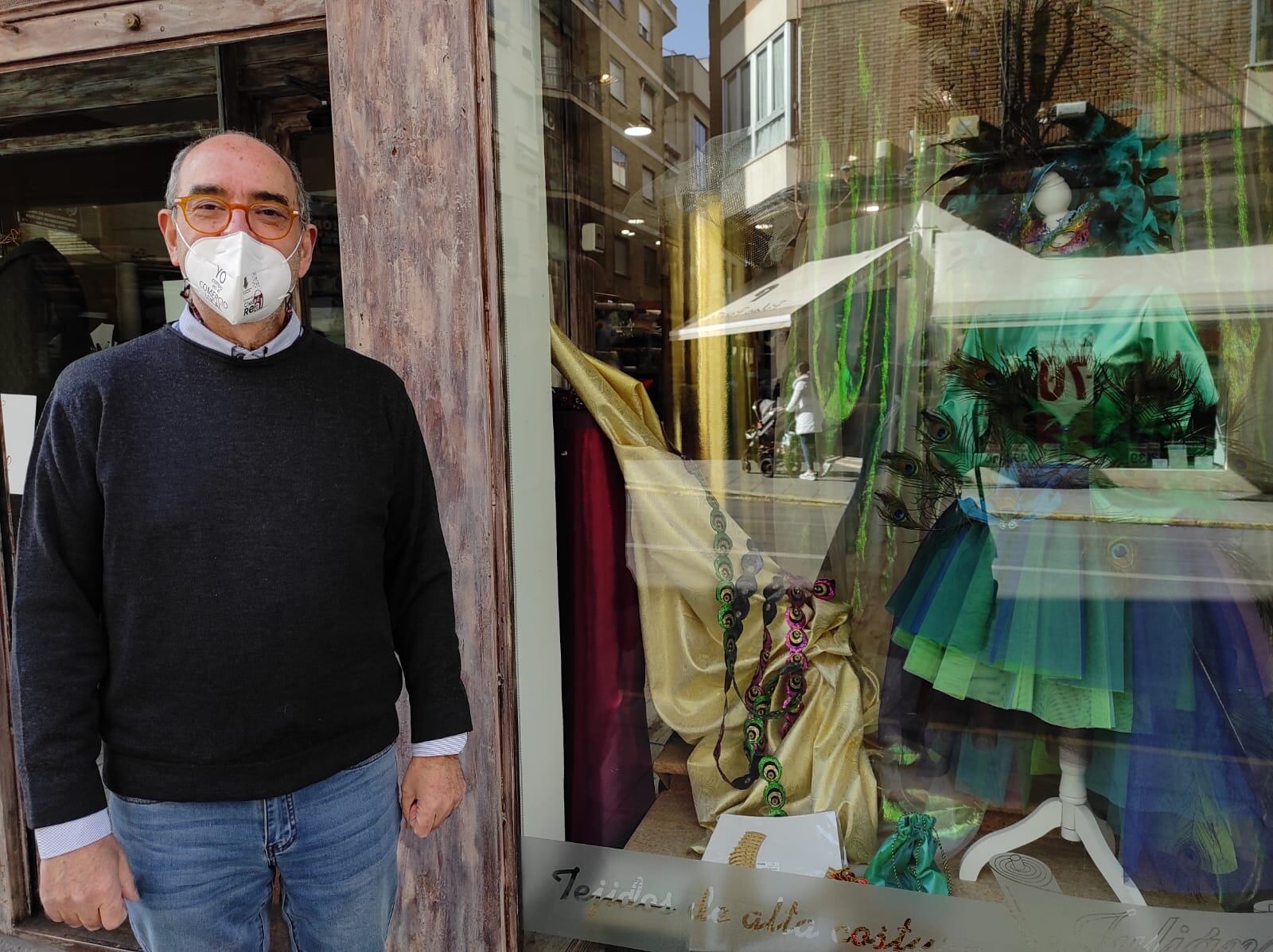 Julian en el escaparate de su tienda, donde se puede ver un traje de Carnaval de una peña