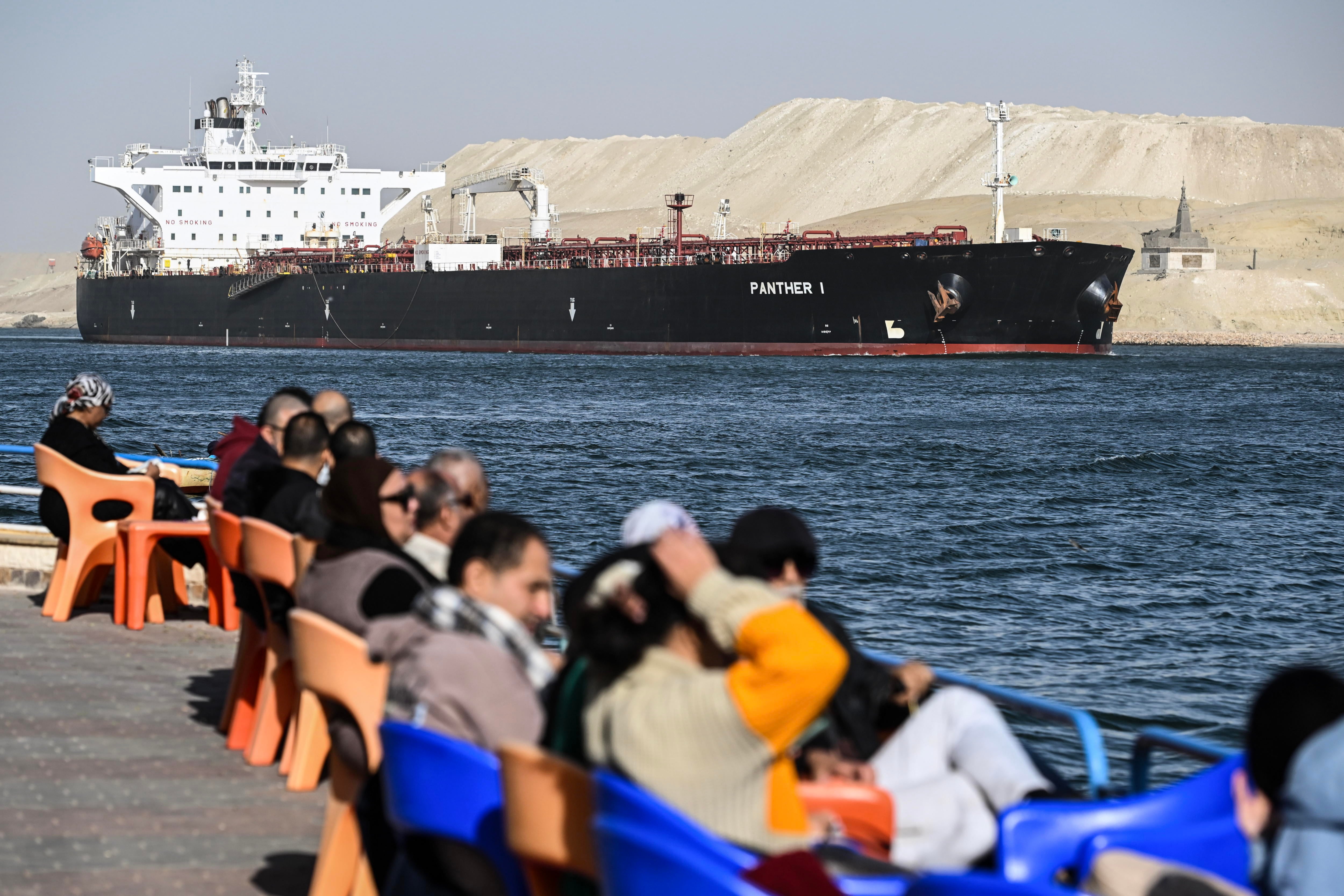 Ismailia (Egipto), 22/12/2023.- La gente observa cómo un barco cruza el Canal de Suez hacia el Mar Rojo.