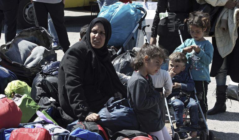 Varias familias sirias esperan para coger un autobús en el Puerto del Pireo en Grecia