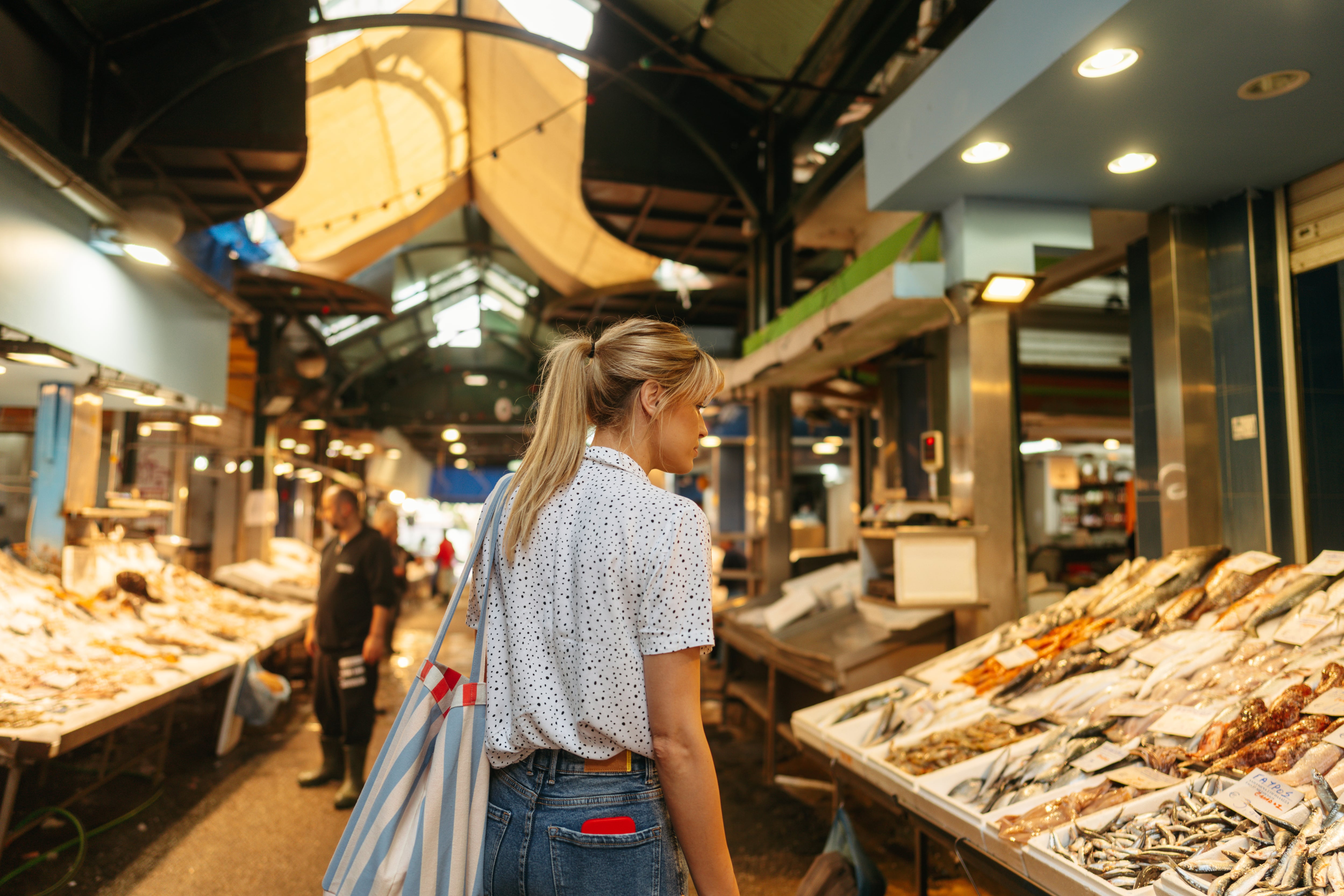 Una mujer observa un puesto de pescado en un Mercado de Abastos.