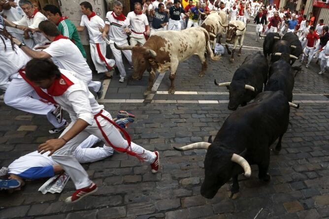 Los mozos corren, por la calle Mercaderes, delante de los toros de la ganadería madrileña de Victoriano del Río que han protagonizado el cuarto encierro de los sanfermines