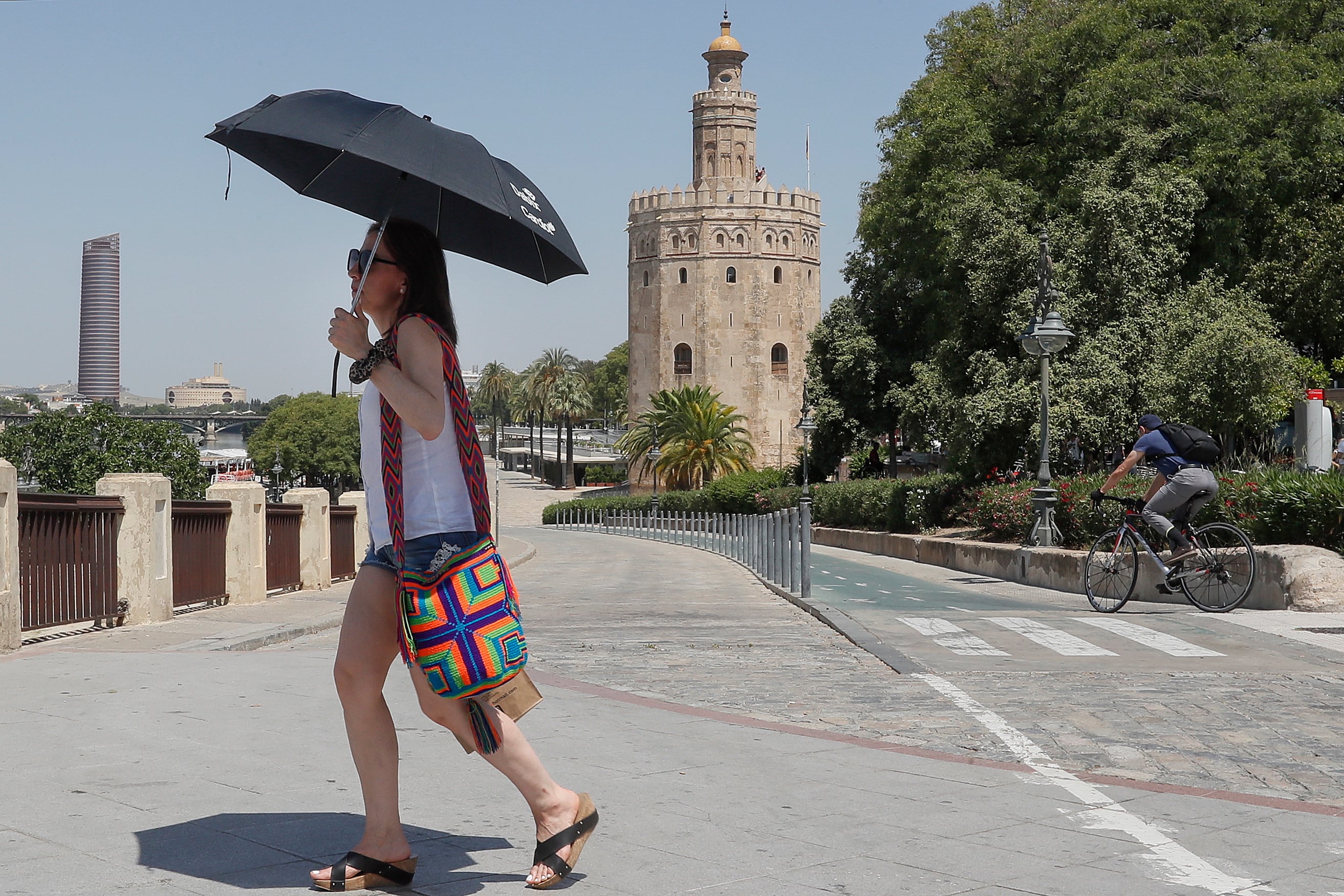 Una turista se cubre con un paraguas mientras camina junto a la Torre del Oro de Sevilla EFE/José Manuel Vidal