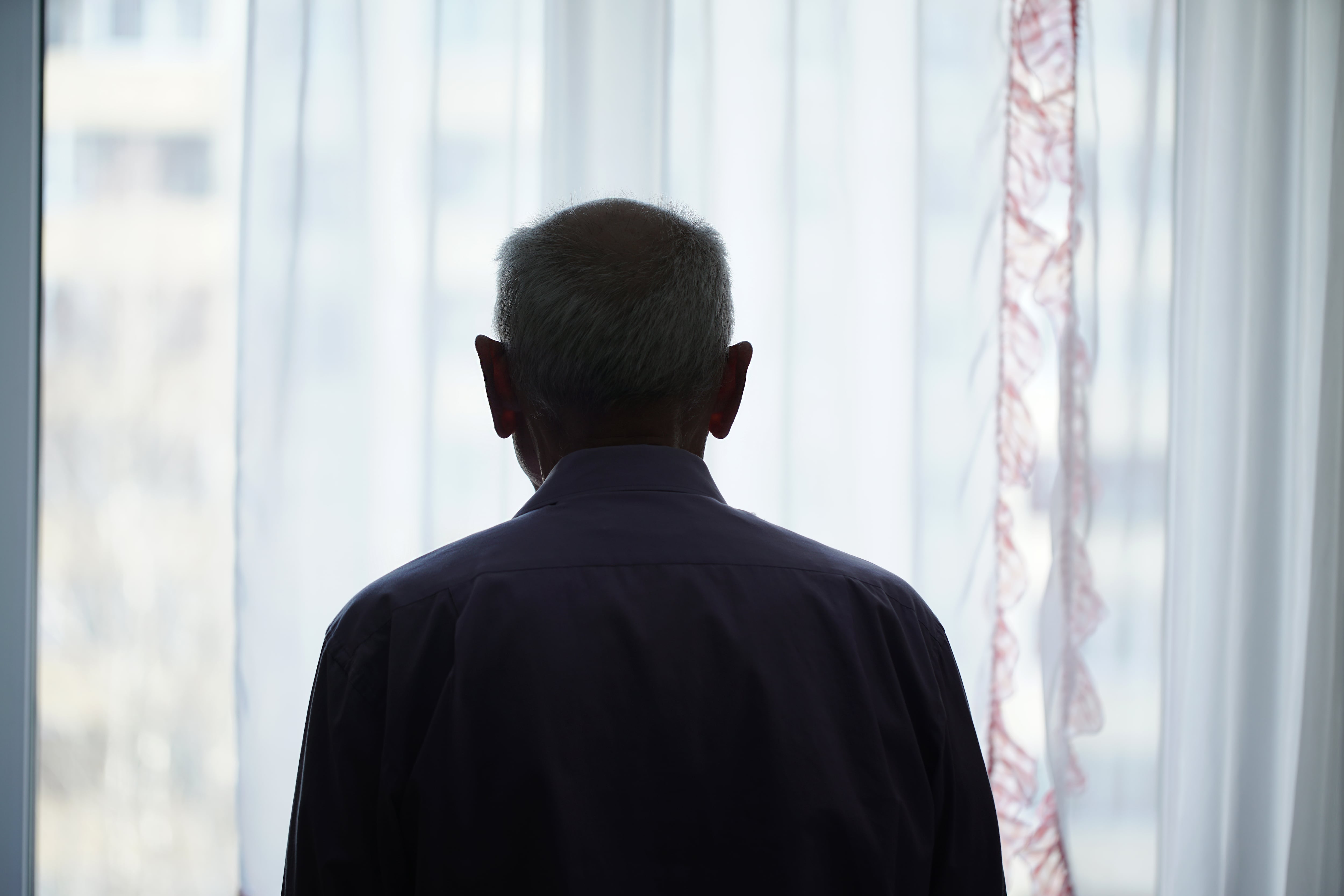 Silueta de hombre mirando por la ventana en una imagen de recurso.