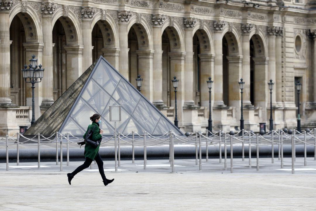 Una mujer pasea cerca del Museo Louvre en París