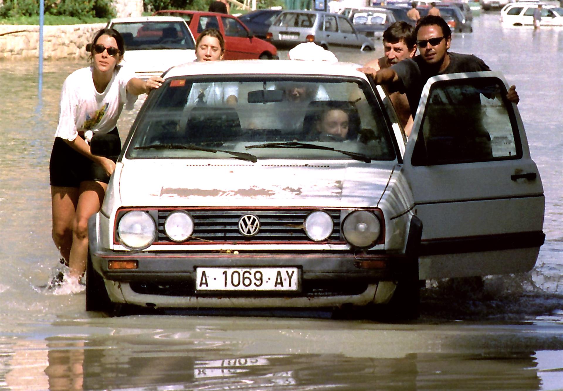 Varias personas empujan un coche para sacarlo de la zona inundada en la playa de San Juan durante las riadas del 30 de septiembre de 1997 en Alicante