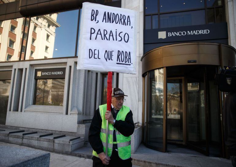 A man protests while holding a banner in Madrid March 11, 2015. The financial authority of tax haven Andorra has taken control of private bank Banca Privada D&#039;Andorra (BPA) after the United States declared the lender as under suspicion for money launderin