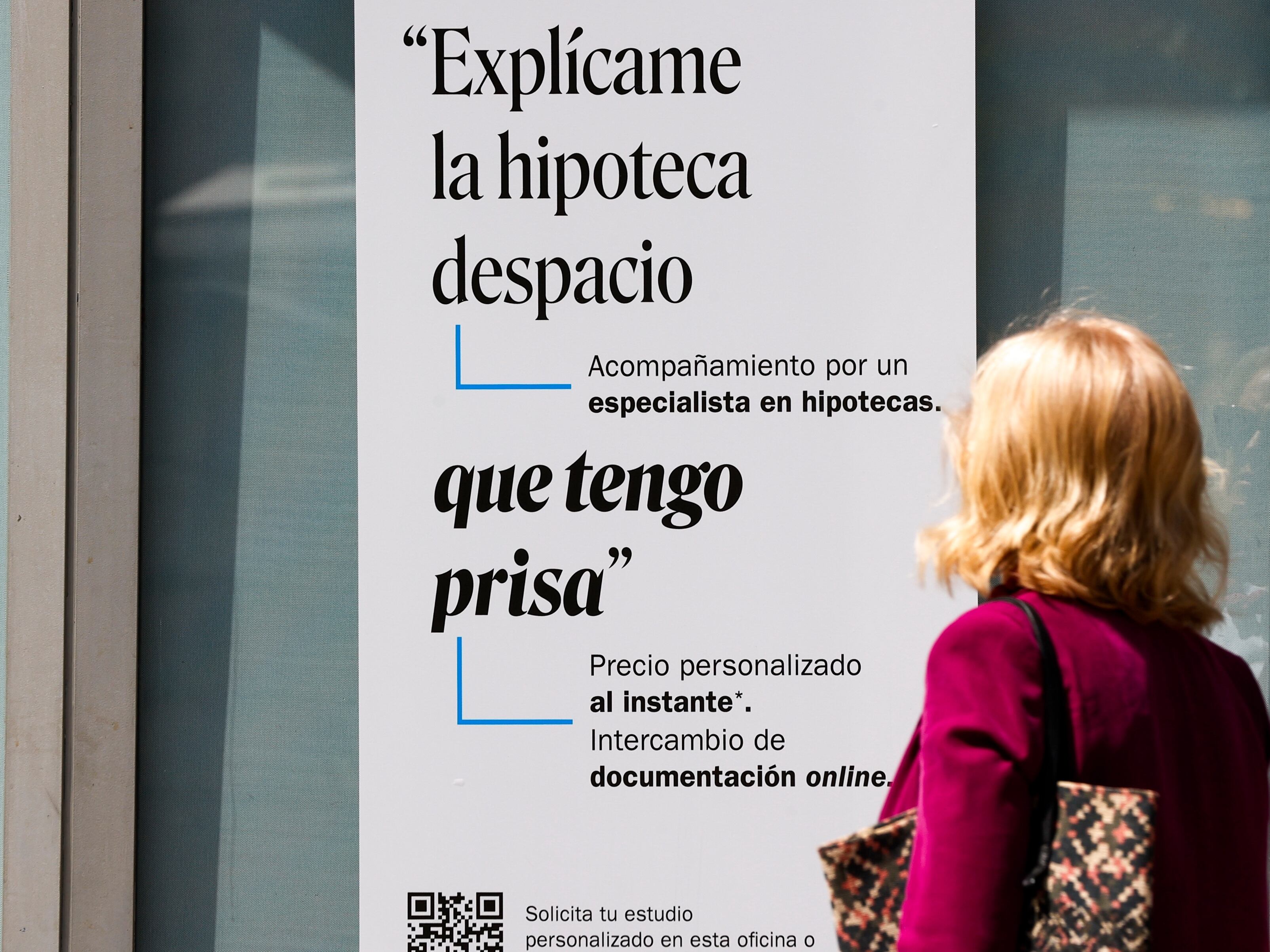 Una mujer ante un cartel de una entidad bancaria