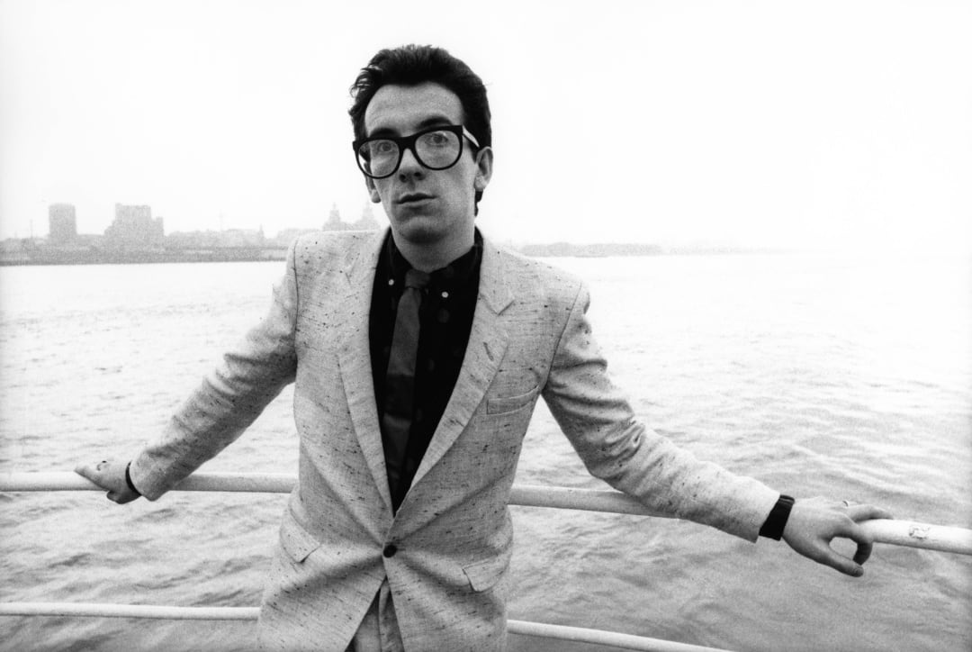 Elvis Costello posa en un ferry con Liverpool al fondo en 1979