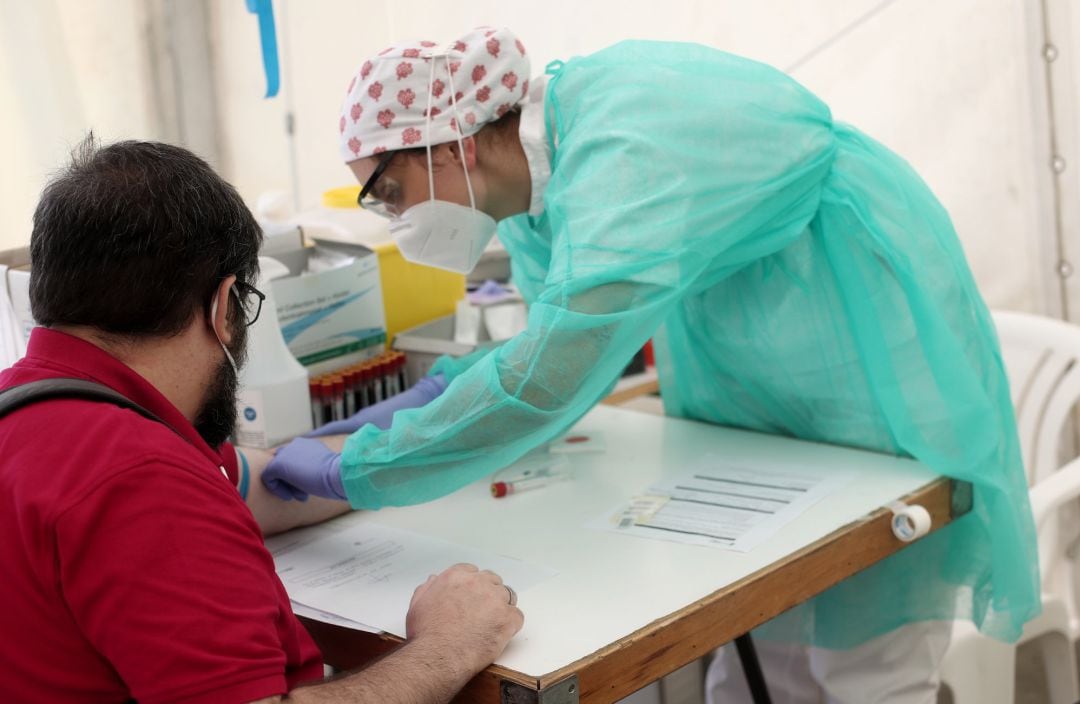 Un sanitario junto a un paciente durante una jornada del test serológico masivo de coronavirus de Torrejón