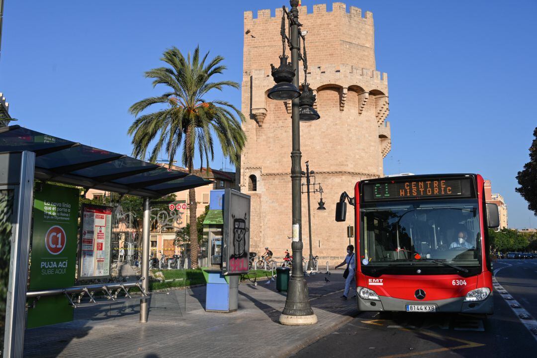 Un autobús de la línea C1 de la EMT de València circula por delante de las torres de Serranos de la ciudad. 