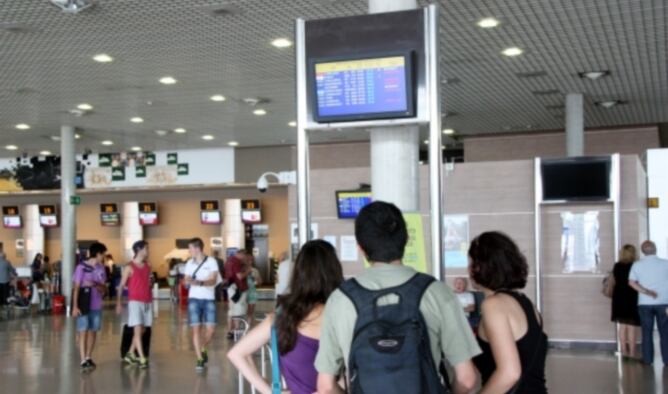 Un grup de viatgers consulta una de les pantalles de la terminal de sortides de l'Aeroport de Reus, amb bona part dels vols cancel·lats
