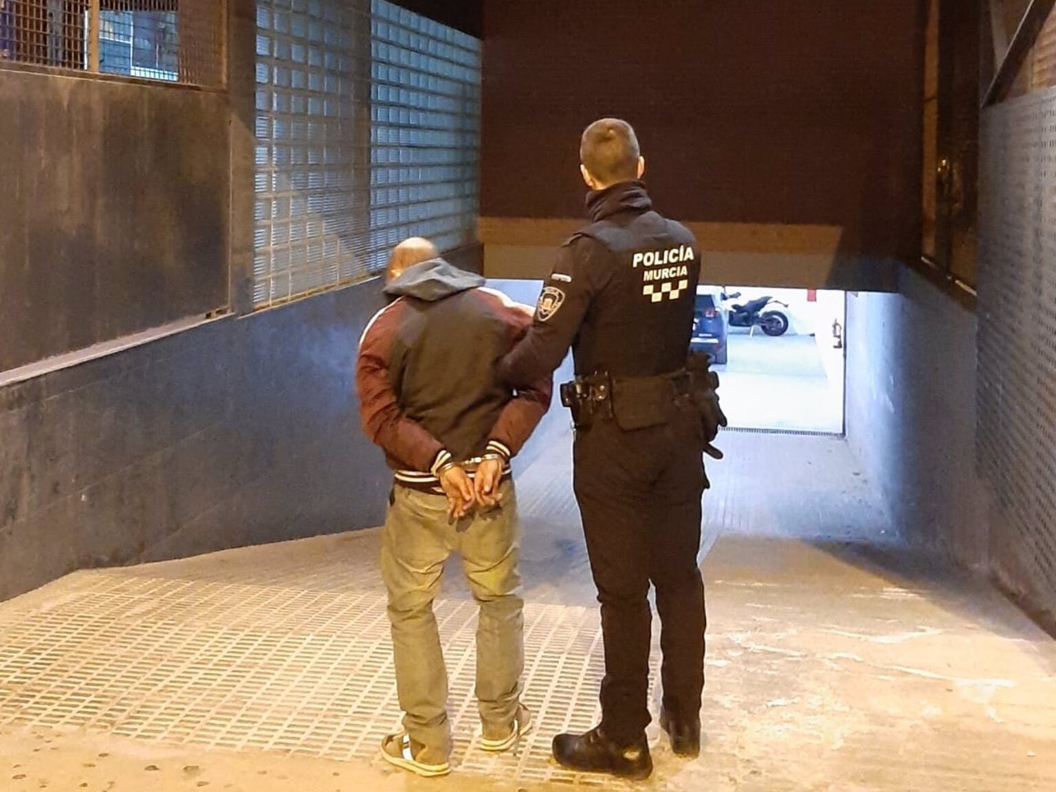 Un agente de la Policía Local de Murcia con el detenido llegando a dependencias policiales