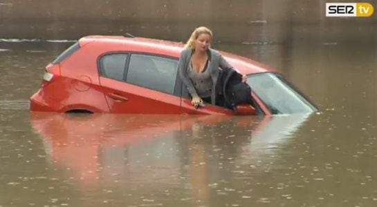 La mujer sale del coche por la ventanilla del copiloto.