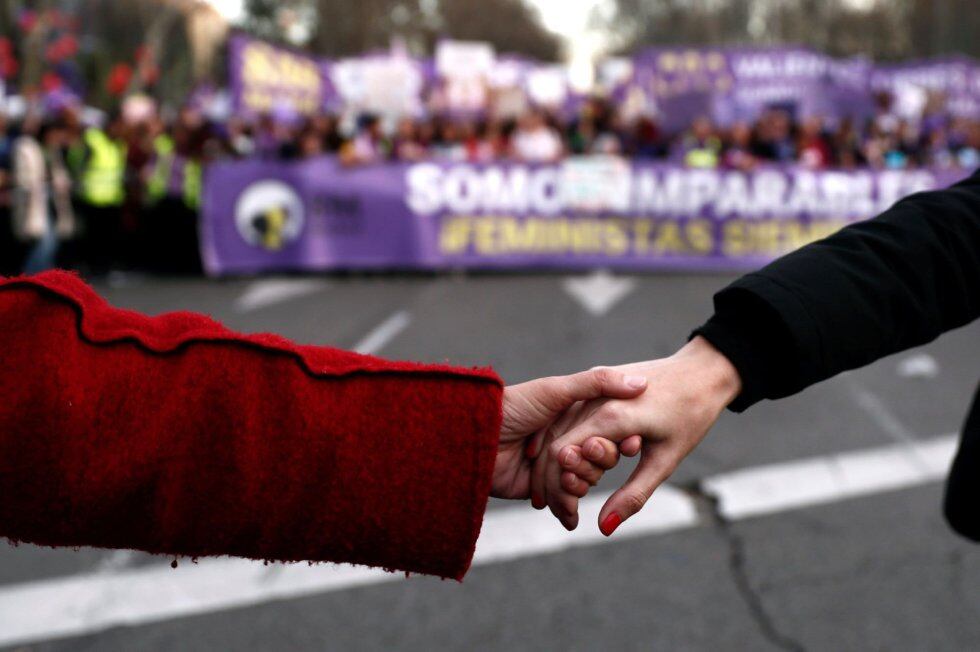 Dos mujeres se dan la mano en una marcha feminista