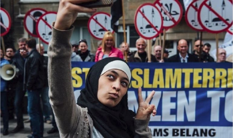 La joven musulmana Zakia Belkhiri se hace una foto con un grupo de manifestantes de extrema derecha en Bélgica. Detrás, con chaqueta rosa, la líder, Anke van Dermeersch