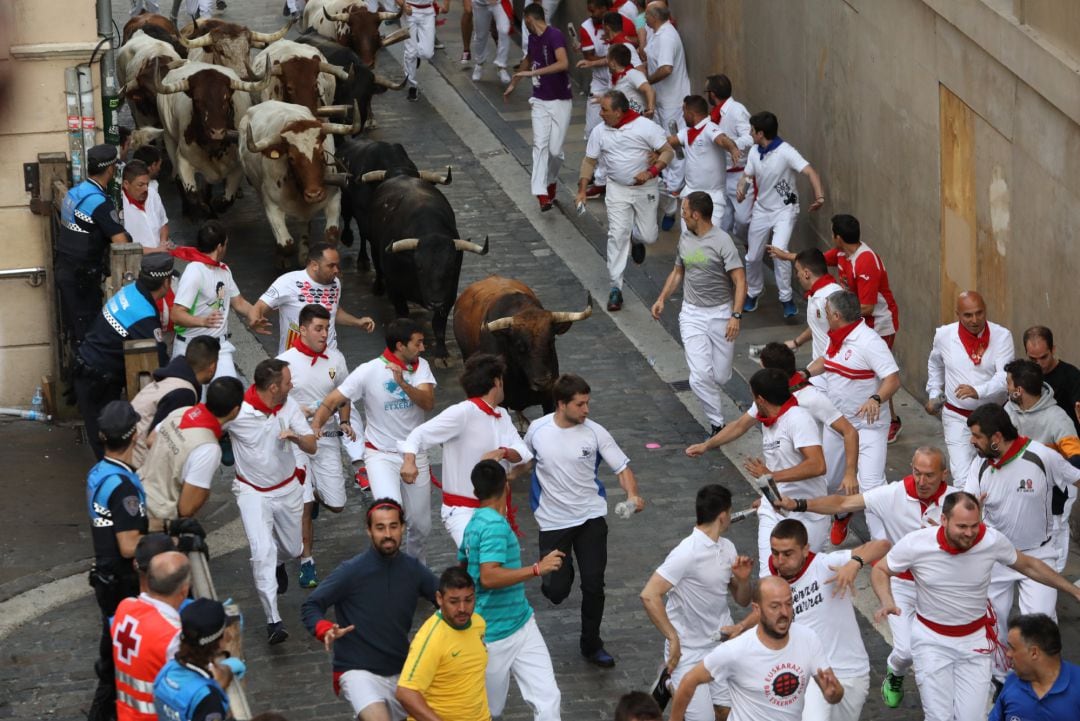 Cientos de personas corren delante de los toros de La Palmosilla en el séptimo encierro de las fiestas de San Fermín celebrado en Pamplona (Navarra). 
 