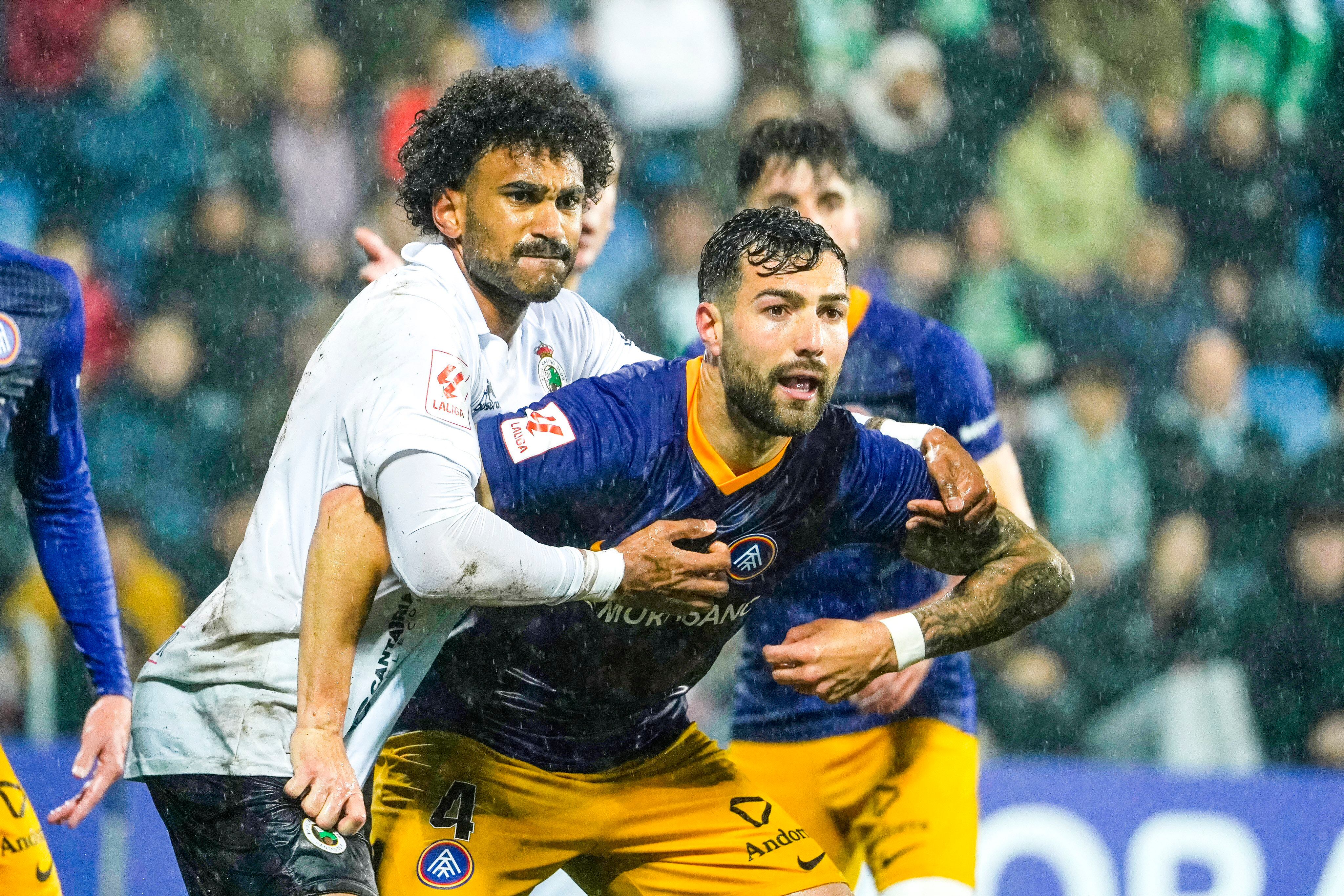Els jugadors de l'FC Andorra lluiten una pilota amb els rivals del Racing de Santander durant el partit disputat divendres a l'Estadi Nacional sota una intensa pluja.