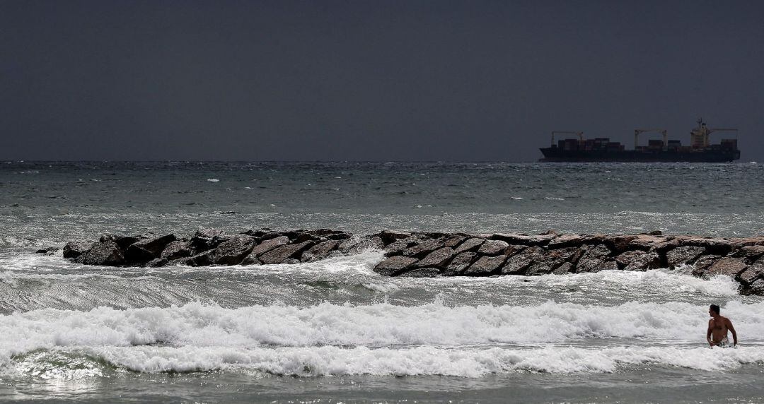 Un hombre se baña este miércoles en la playa de Pinedo de Valéncia, donde se ha izado la bandera amarilla por mar rizada y se permite el baño con precaución.