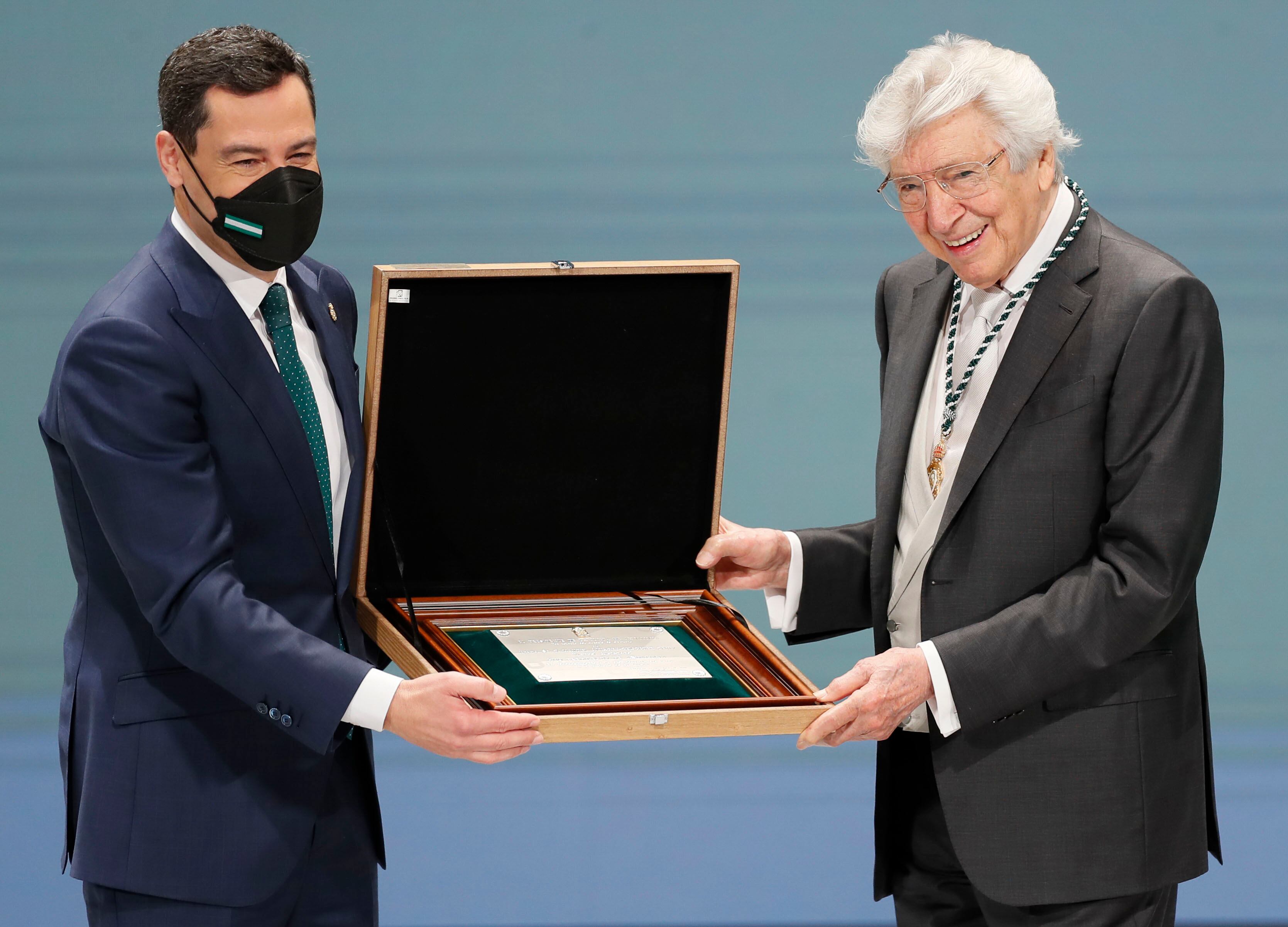 SEVILLA, 28/02/2022.- El presidente de la Junta de Andalucía, Juanma Moreno (i), entrega la distinción de Hijo Predilecto de Andalucía al compositor Manuel Alejandro (d) durante la ceremonia de entrega de medallas del Día de Andalucía celebrado este lunes en el teatro de la maestranza de Sevilla. EFE/José Manuel Vidal
