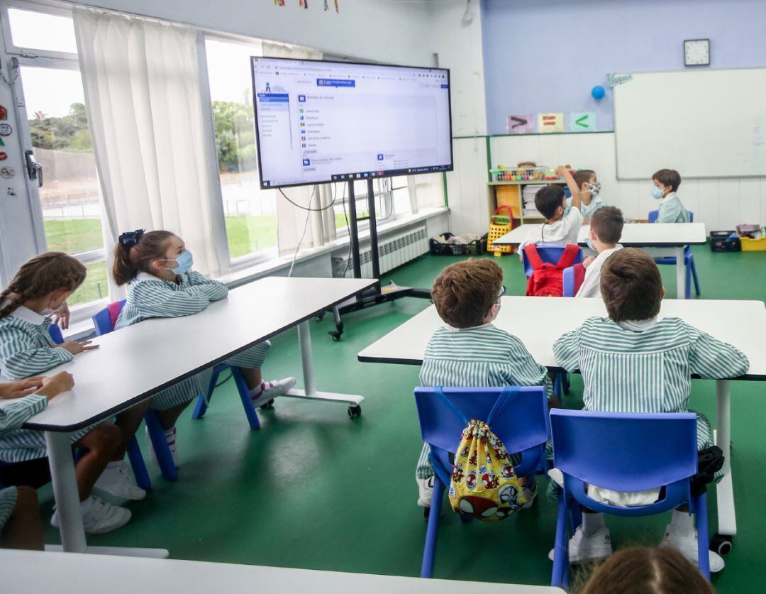 Varios niños escuchan las explicaciones de su profesora en una clase del colegio Virgen de Europa en Boadilla del Monte, Madrid (España). 