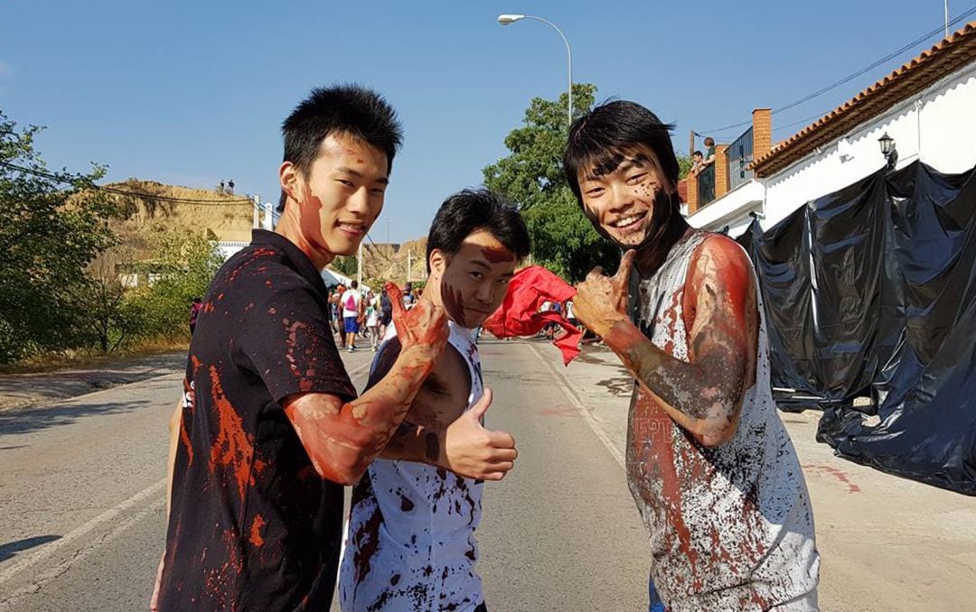 Tres turistas asiáticos en la carrera del Cascamorras en Guadix (Granada), como muestra de la atracción internacional de la fiesta que esta ciudad comparte con Baza