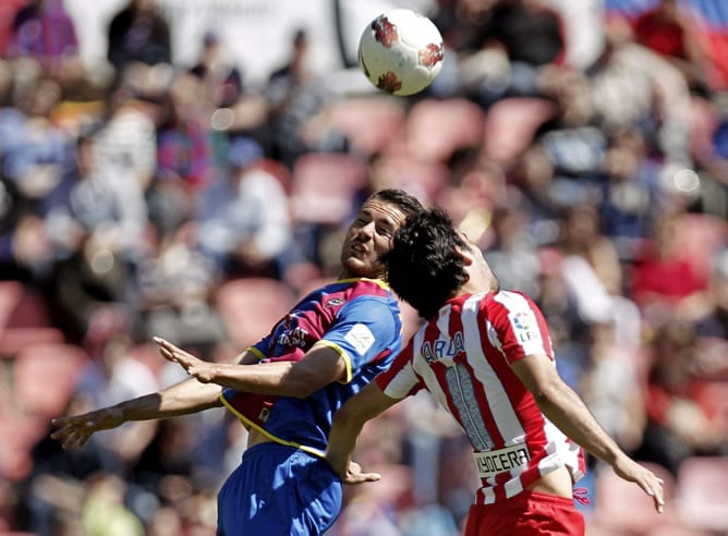 El centrocampista del Levante Xavi Torres pelea un balón aéreo con el centrocampista del Atlético de Madrid, Arda Turan, durante la trigésima segunda jornada de liga en Primera División disputado hoy en el Estadio Ciutat de València