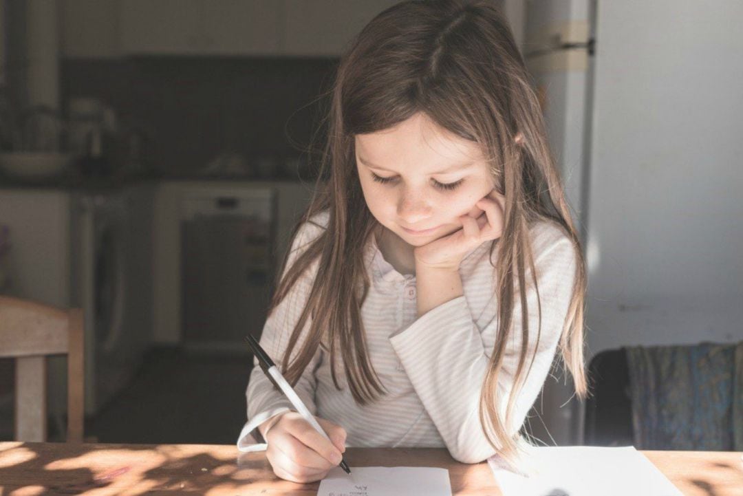 Una niña hace los deberes escolares. 