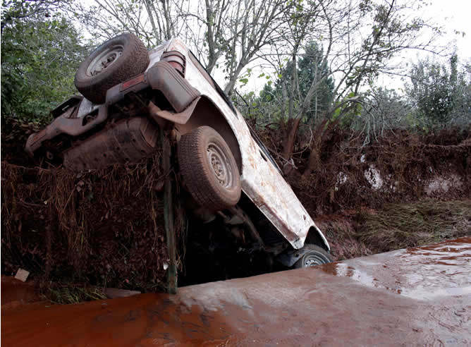 Un coche volcado dentro de una marea de lodo tóxico procedente de una empresa de aluminio en Devecser, a 167 kilómetros al suroeste de Budapest (Hungría), después de la rotura de un dique de &quot;barro rojo&quot;, una sustancia química muy corrosiva y alcalina, de una empresa de aluminio cerca de la localidad de Ajka