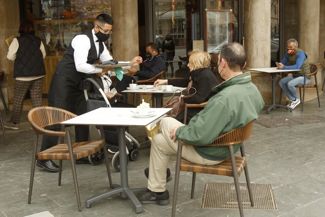 Un camarero atiende a varios clientes en la terraza de un bar