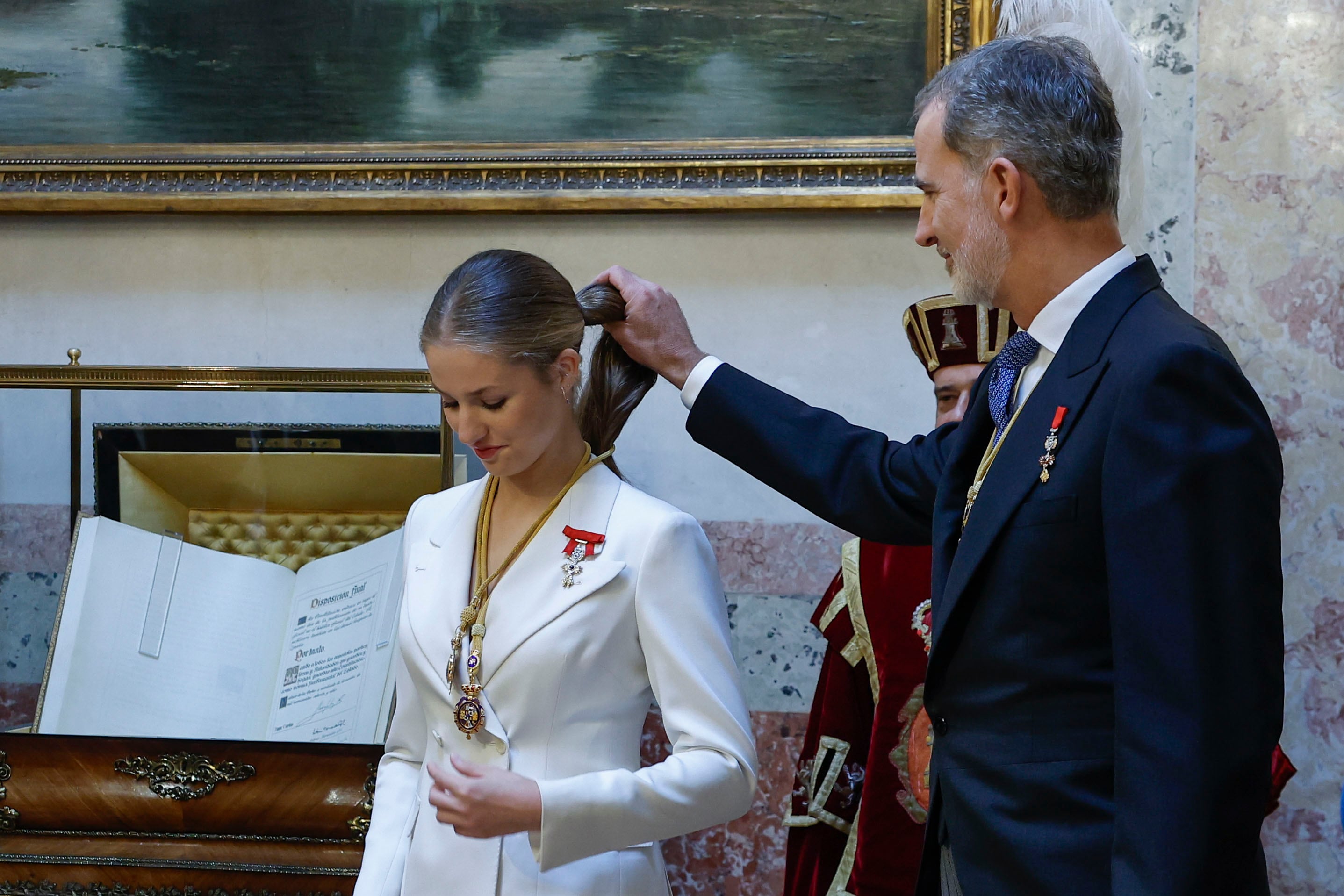 La princesa Leonor (c), es ayudada por su padre, Felipe VI, tras serle impuestas las Medallas del Congreso y Senado en el escritorio del Congreso.