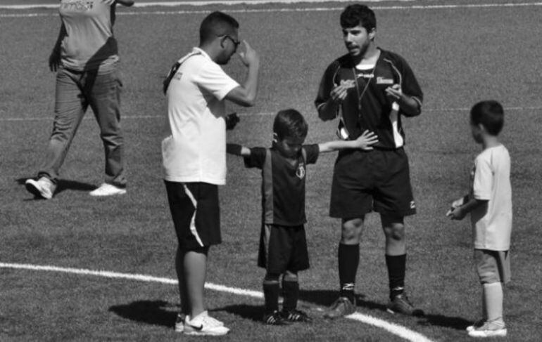 Alejandro Rodríguez separa a uno de los entrenadores y al árbitro durante un partido de fútbol infantil.