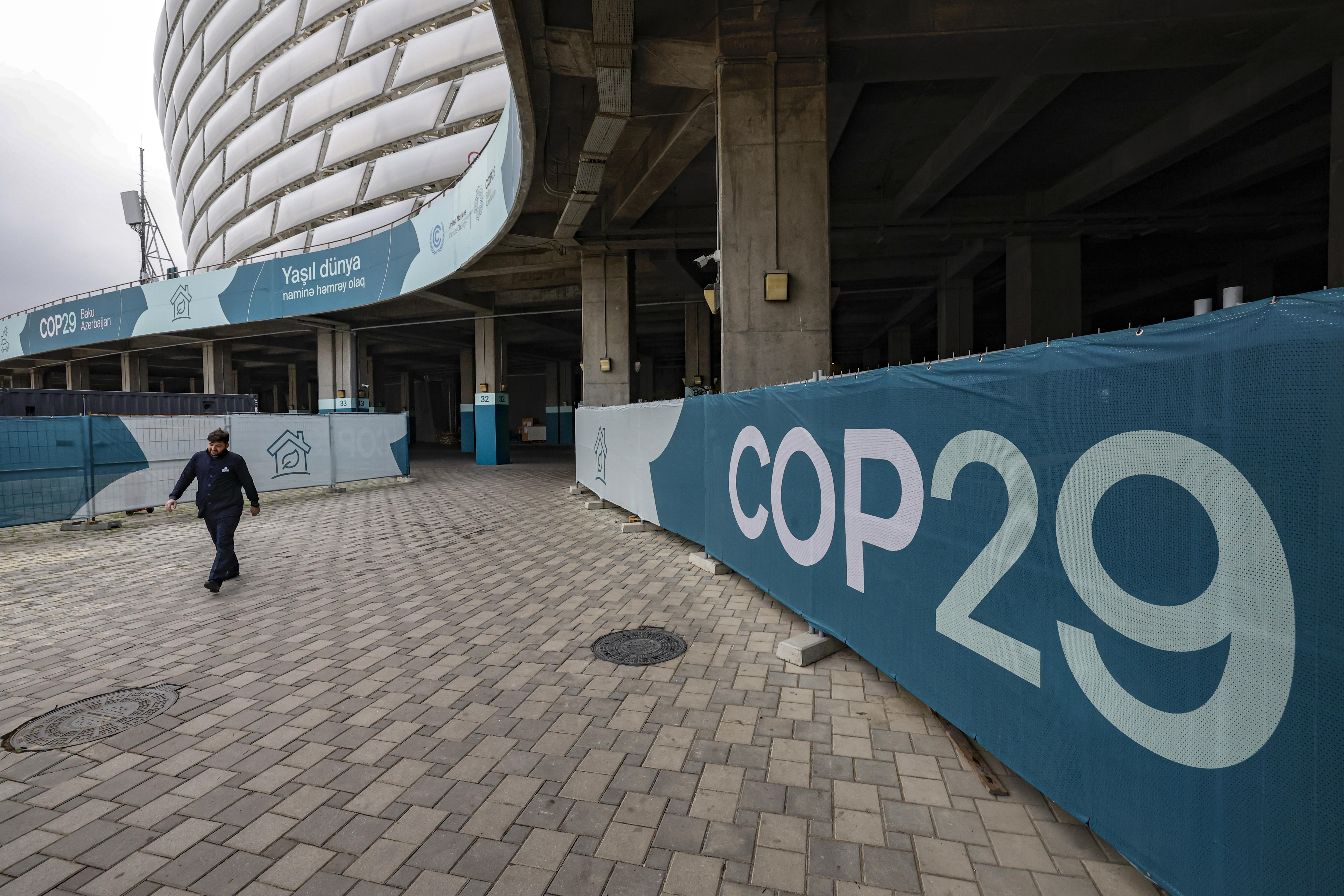 Un hombre pasa por una instalación con el logotipo de la COP29 cerca de la sede de la Conferencia de las Naciones Unidas sobre el Cambio Climático en Bakú