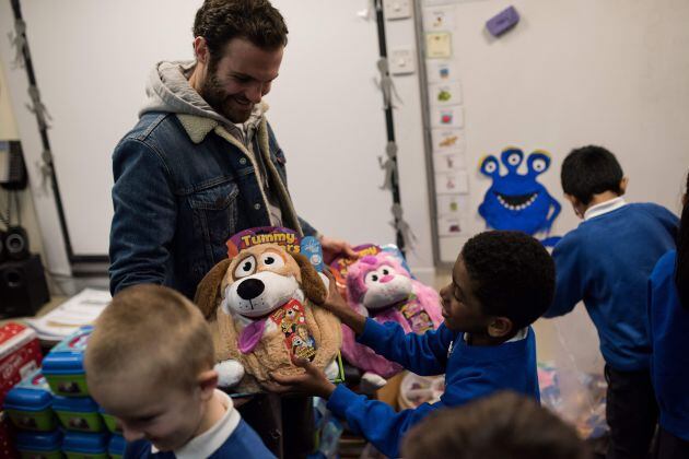 Juan Mata da regalos a unos niños en una visita de la fundación del Manchester United