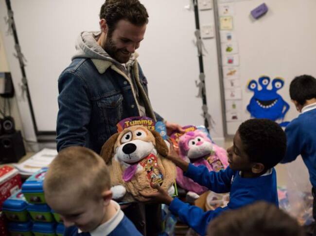 Juan Mata da regalos a unos niños en una visita de la fundación del Manchester United