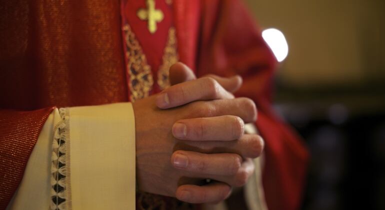 Imagen de un sacerdote orando con las manos entrelazadas.