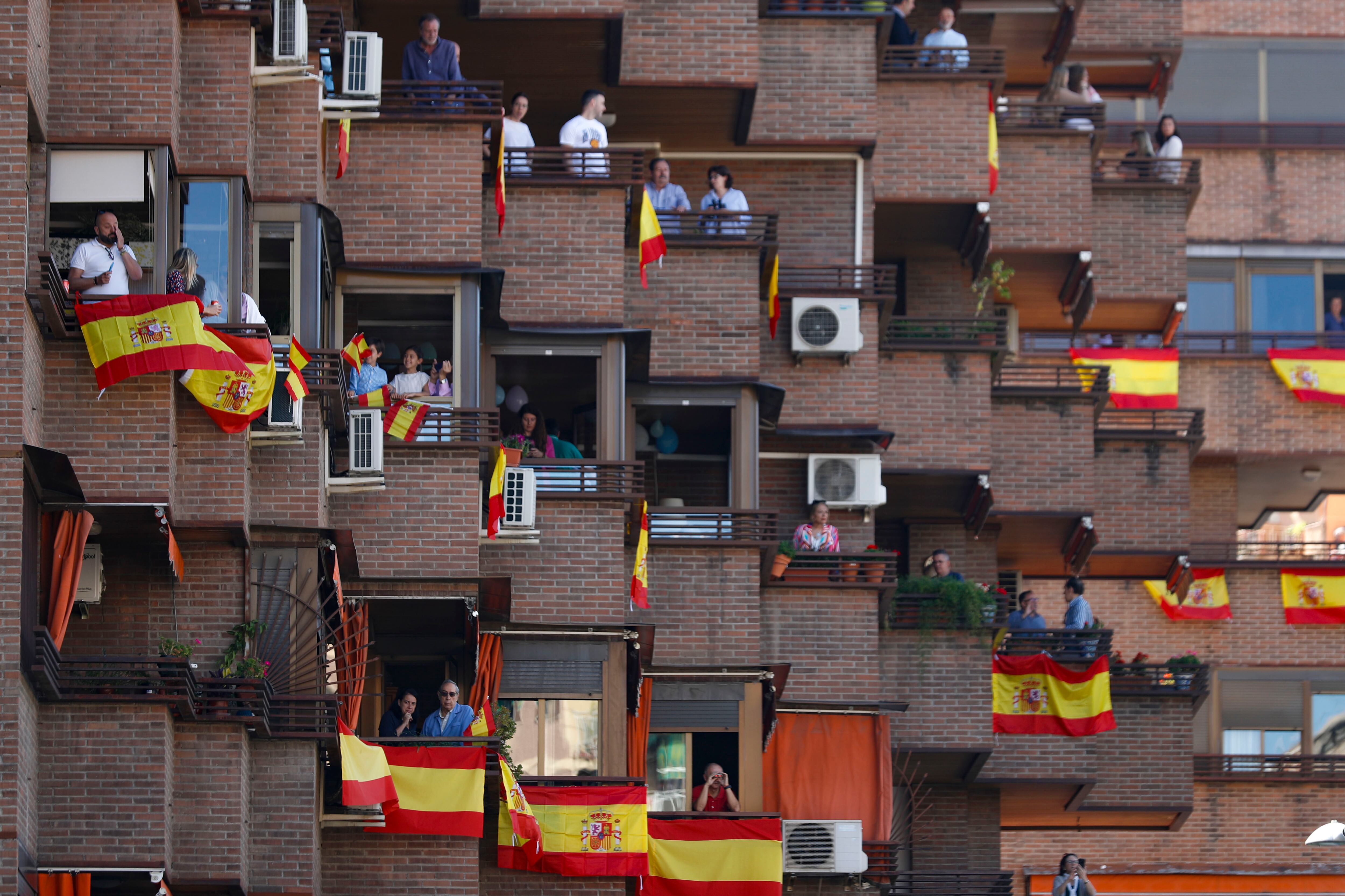 Vecinos de Granada esperan desde sus balcones, engalanados con banderas de España, a que comience el desfile del Día de las Fuerzas Armadas