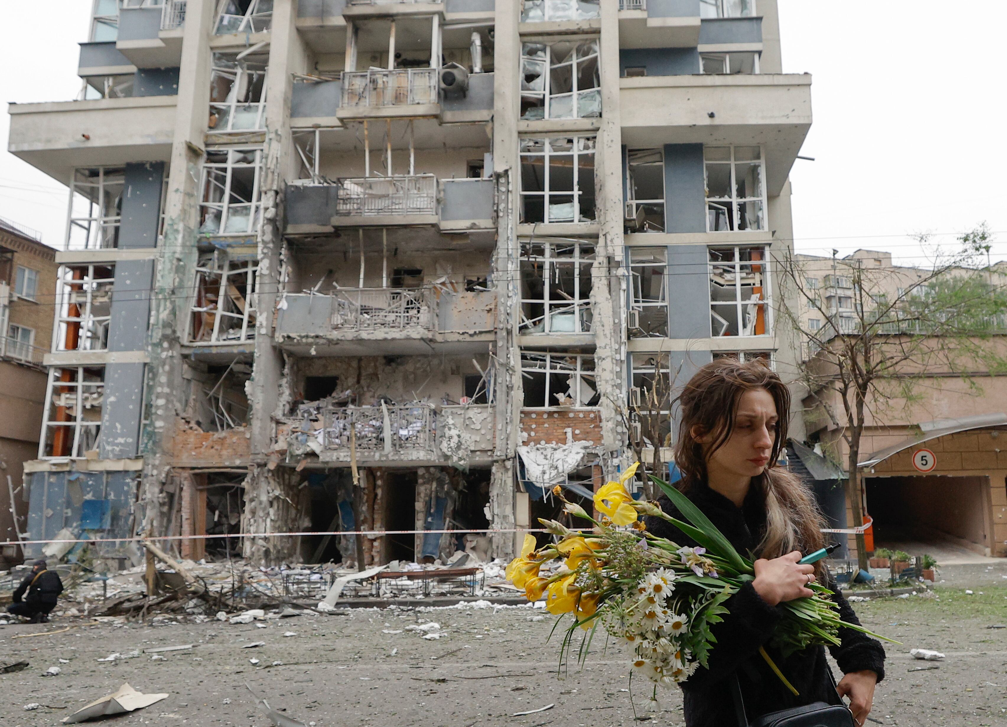 Una mujer camina cerca de un edificio residencial alcanzado por los misiles rusos este domingo en Kiev. EFE/EPA/SERGEY DOLZHENKO