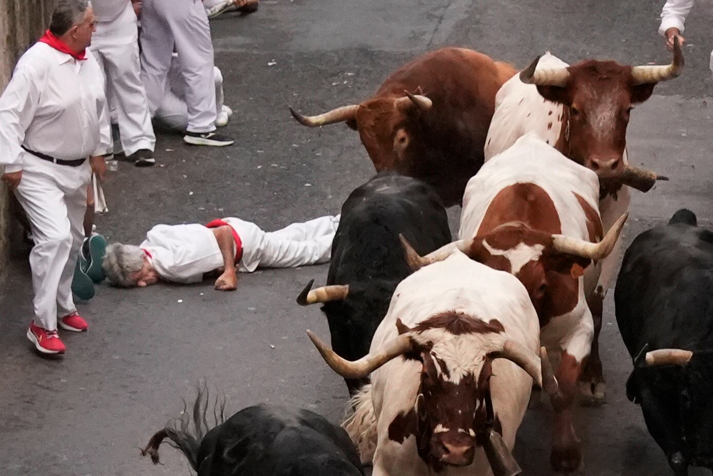 El mozo en el suelo tras sufrir el percance con uno de los toros de la ganadería de Jandilla en la cuesta de Santo Domingo durante el sexto encierro de los Sanfermines. EFE/Sergio Martín